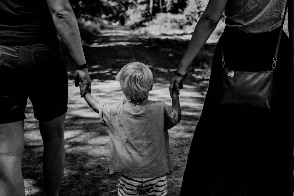 Enfant qui tient les mains de ses parents - Rainbow Audiologie